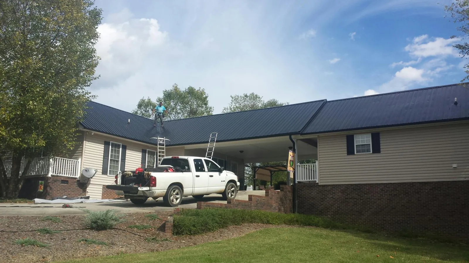 Black metal roof over a home and attached breezeway with ladders set in Uniontown